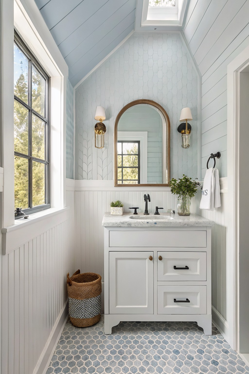 Cozy bathroom with crisp white shiplap wainscoting, pale blue ceiling, white vanity, and blue hex tile floor