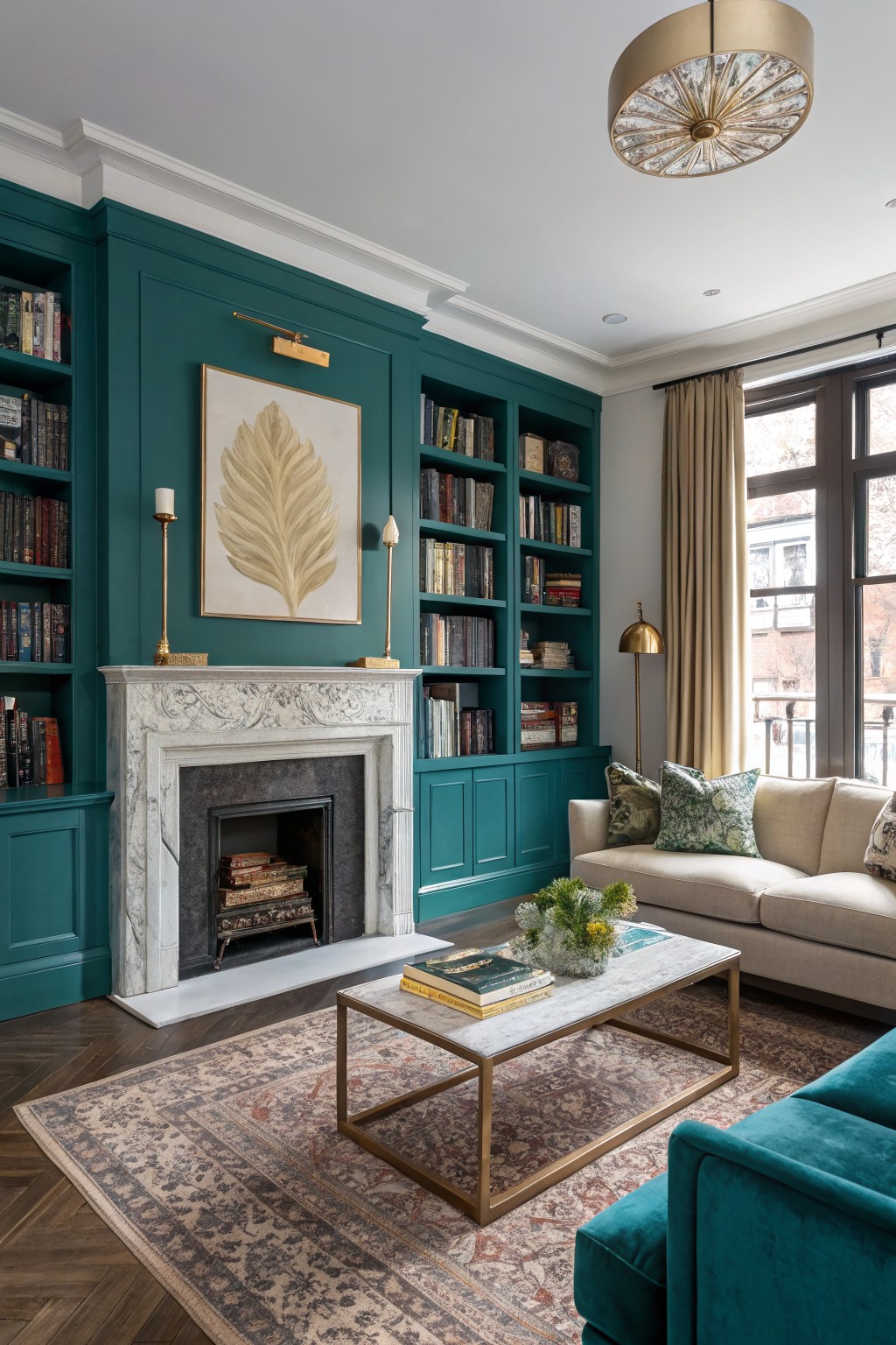 Deep teal walls and bookcases in a living room with marble fireplace, cream sofa, gold accents, and wood floors