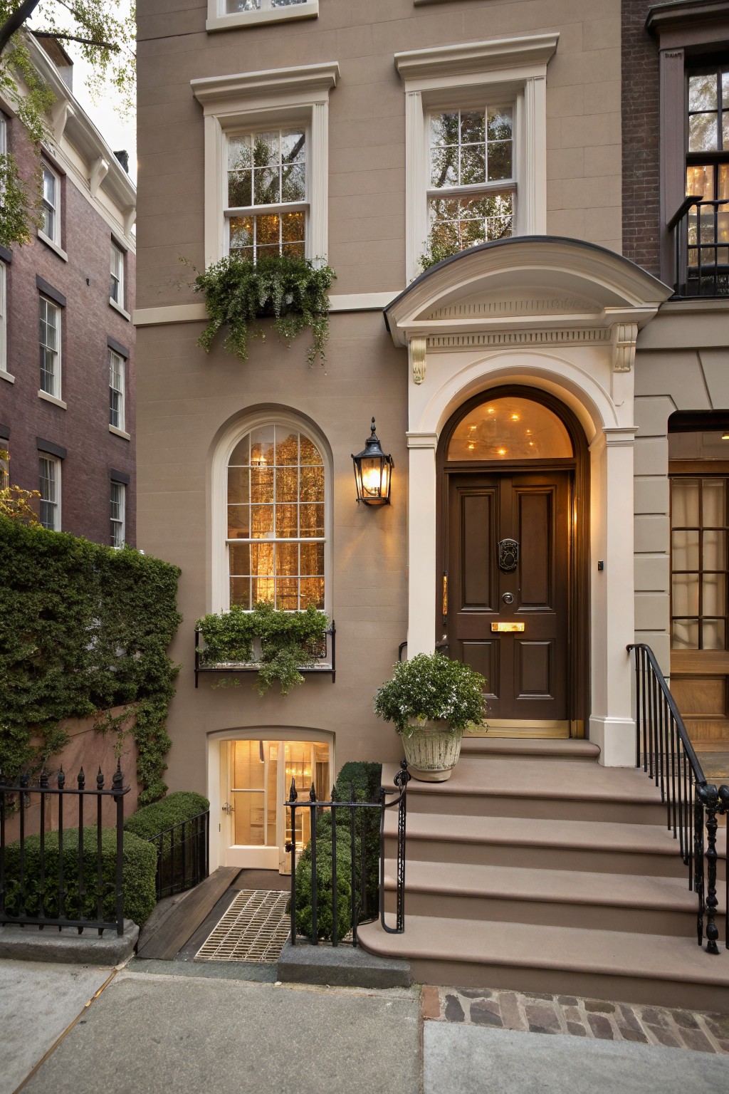 A townhouse exterior painted in a soft greige color with stone steps leading to the front door.