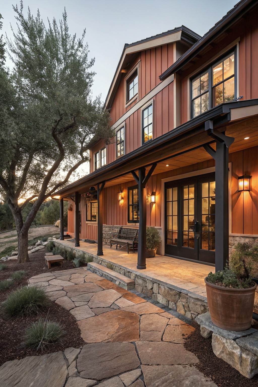Warm red siding on a rustic farmhouse exterior with dark trim and a stone porch.