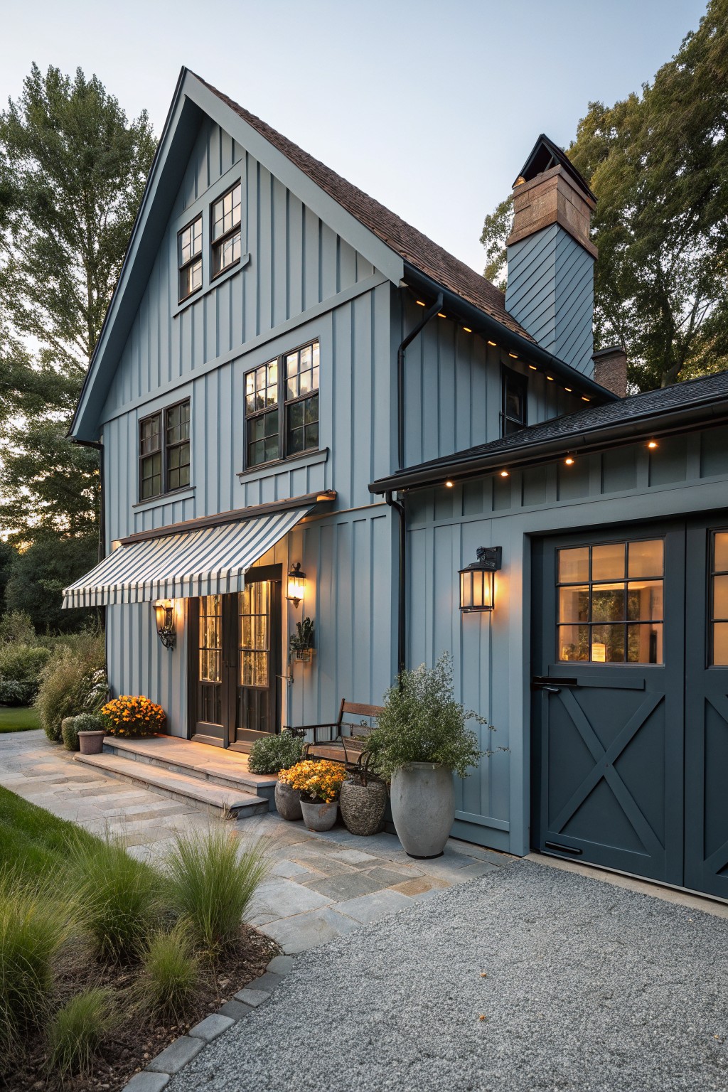 Light blue gray siding covers the exterior of a two story farmhouse with a dark roof and gravel driveway.