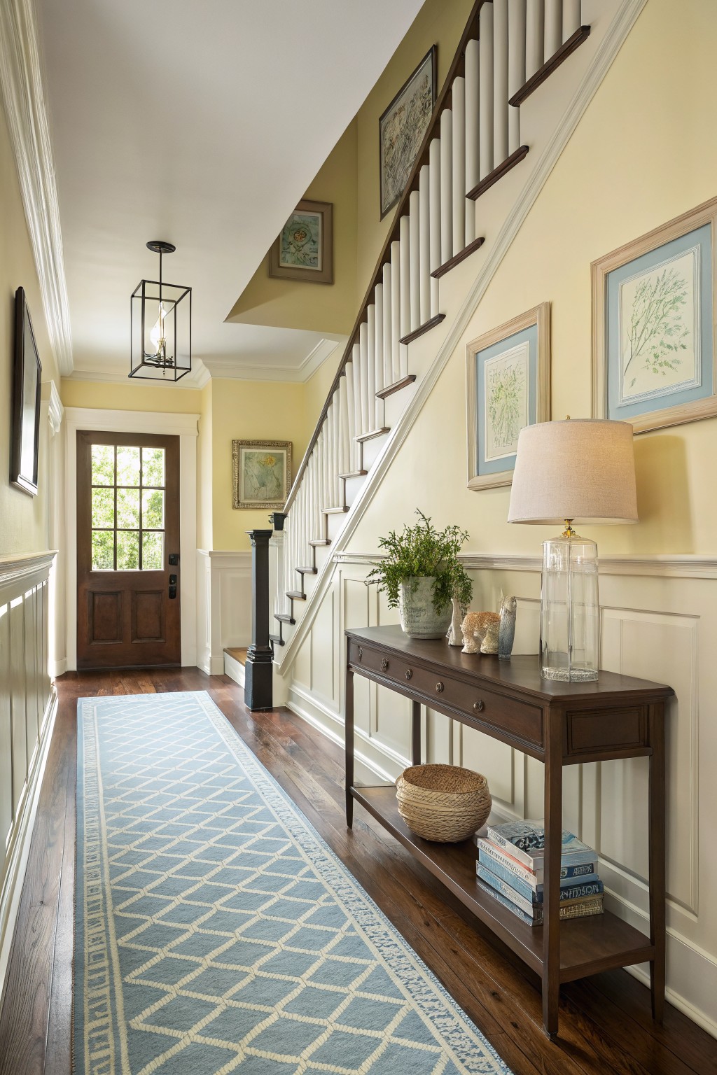 Light yellow walls line a traditional entry hall with a staircase and console table.