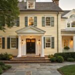 A pale yellow house exterior with white trim and columns around the front door.