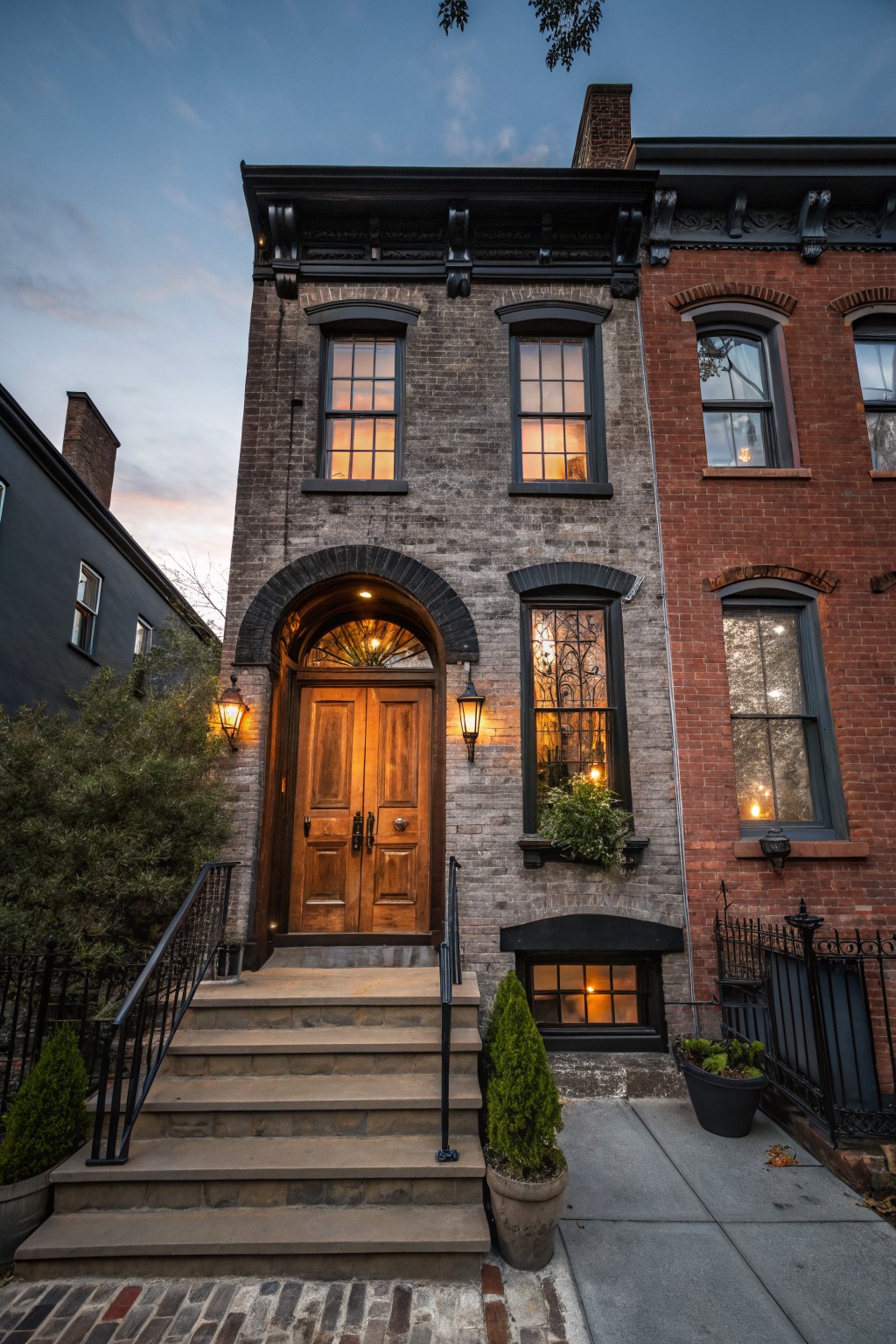 A row house exterior with dark charcoal gray brick and black trim around the windows and archway.