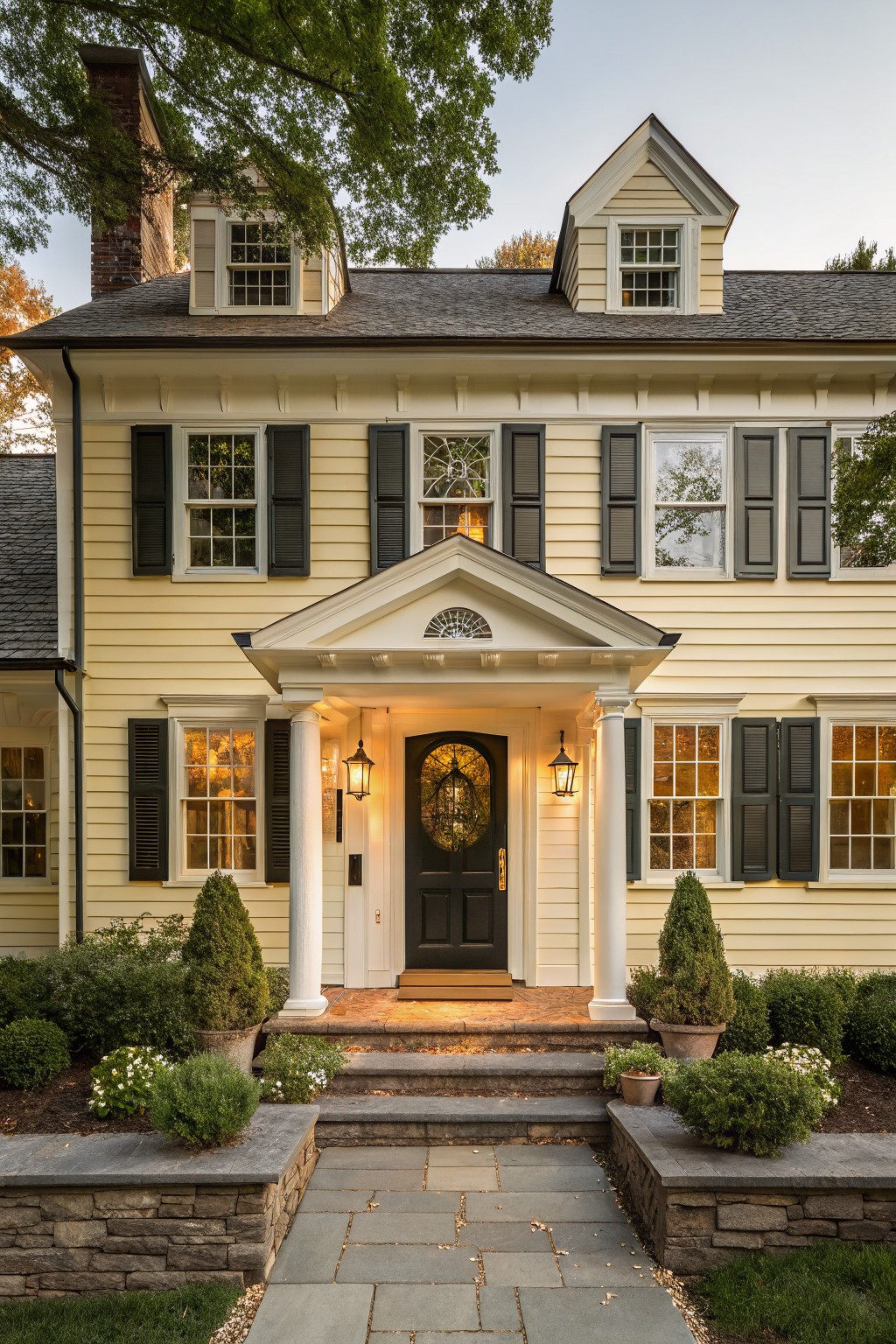 A two-story house with soft yellow siding and white trim around the front entrance.