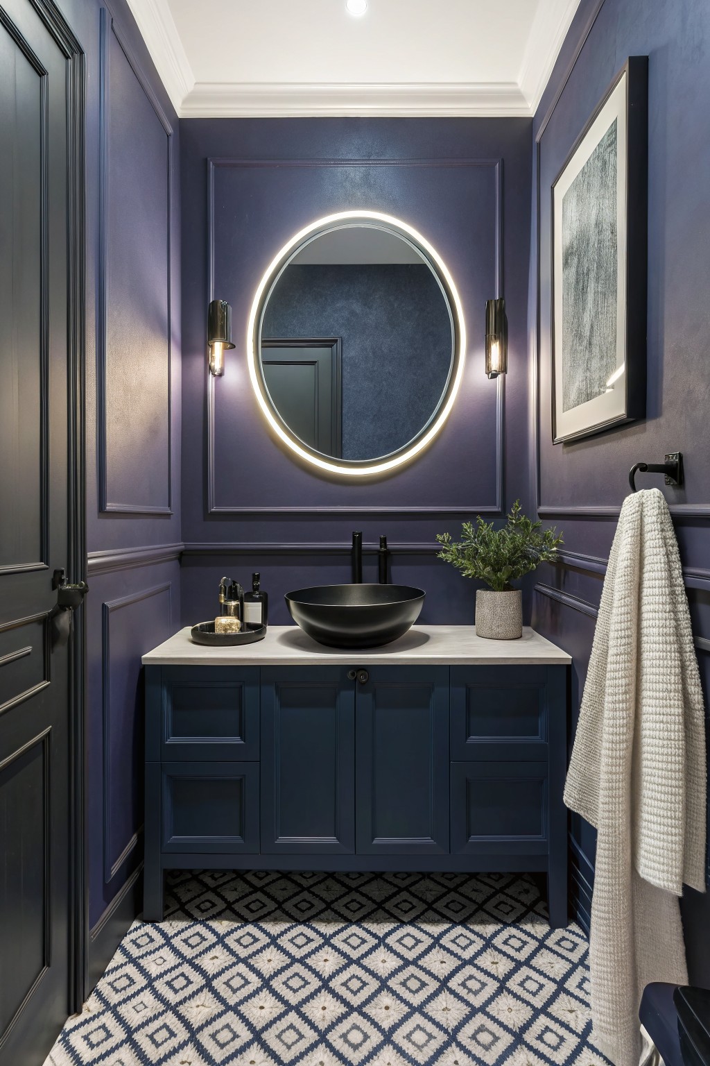 A bathroom featuring deep navy blue walls with white trim and a round backlit mirror above a dark vanity.