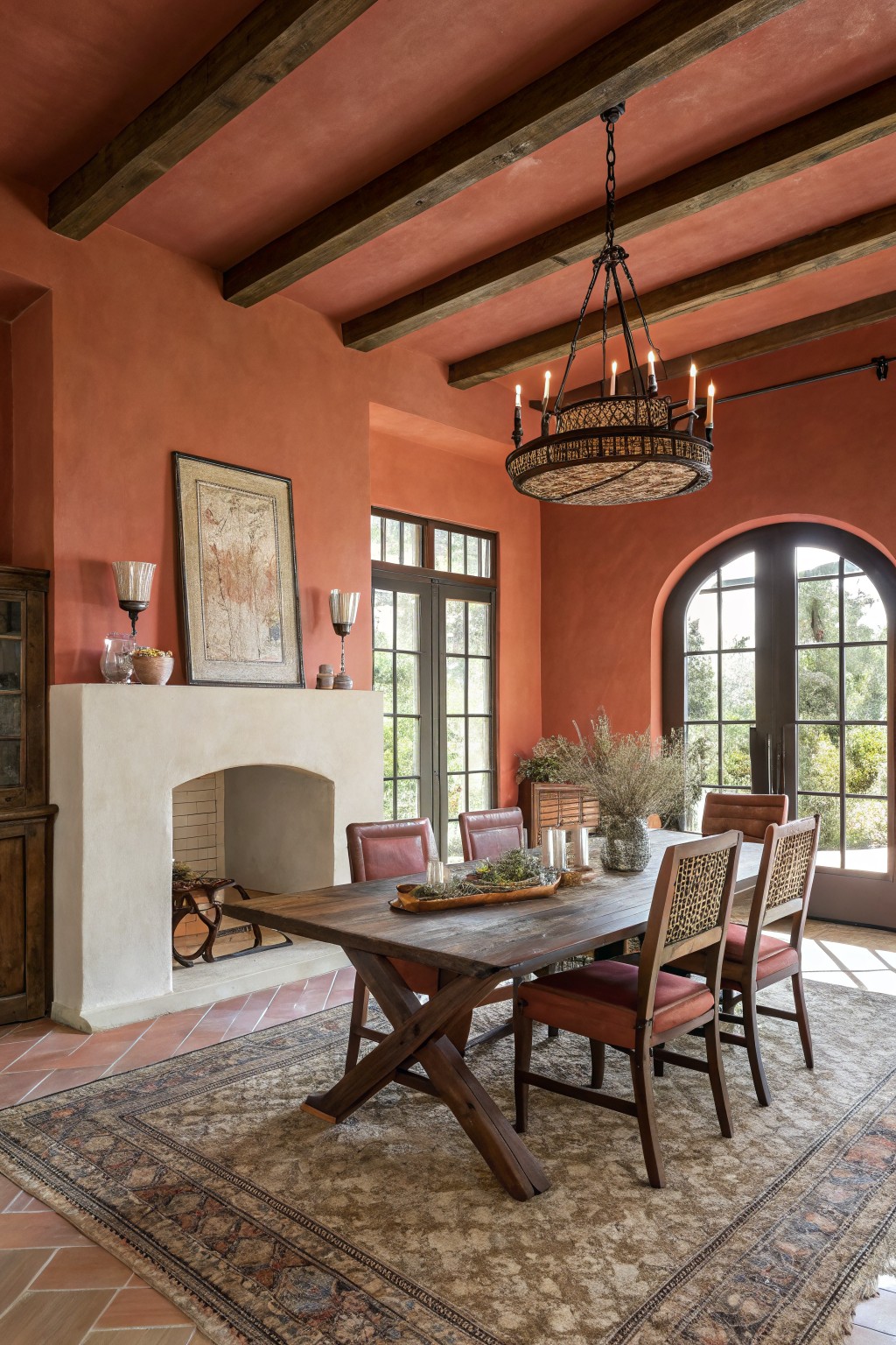 Warm terracotta walls in a dining room with wood beams and a large table.