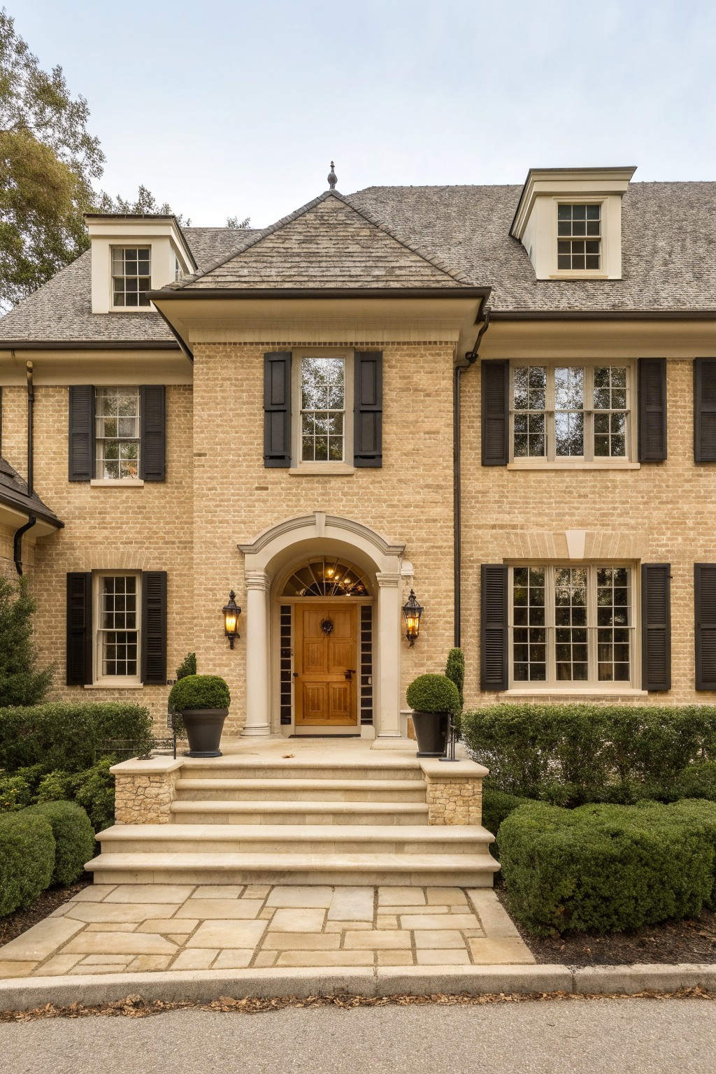 A house exterior finished in warm beige brick with light stone steps and trim.