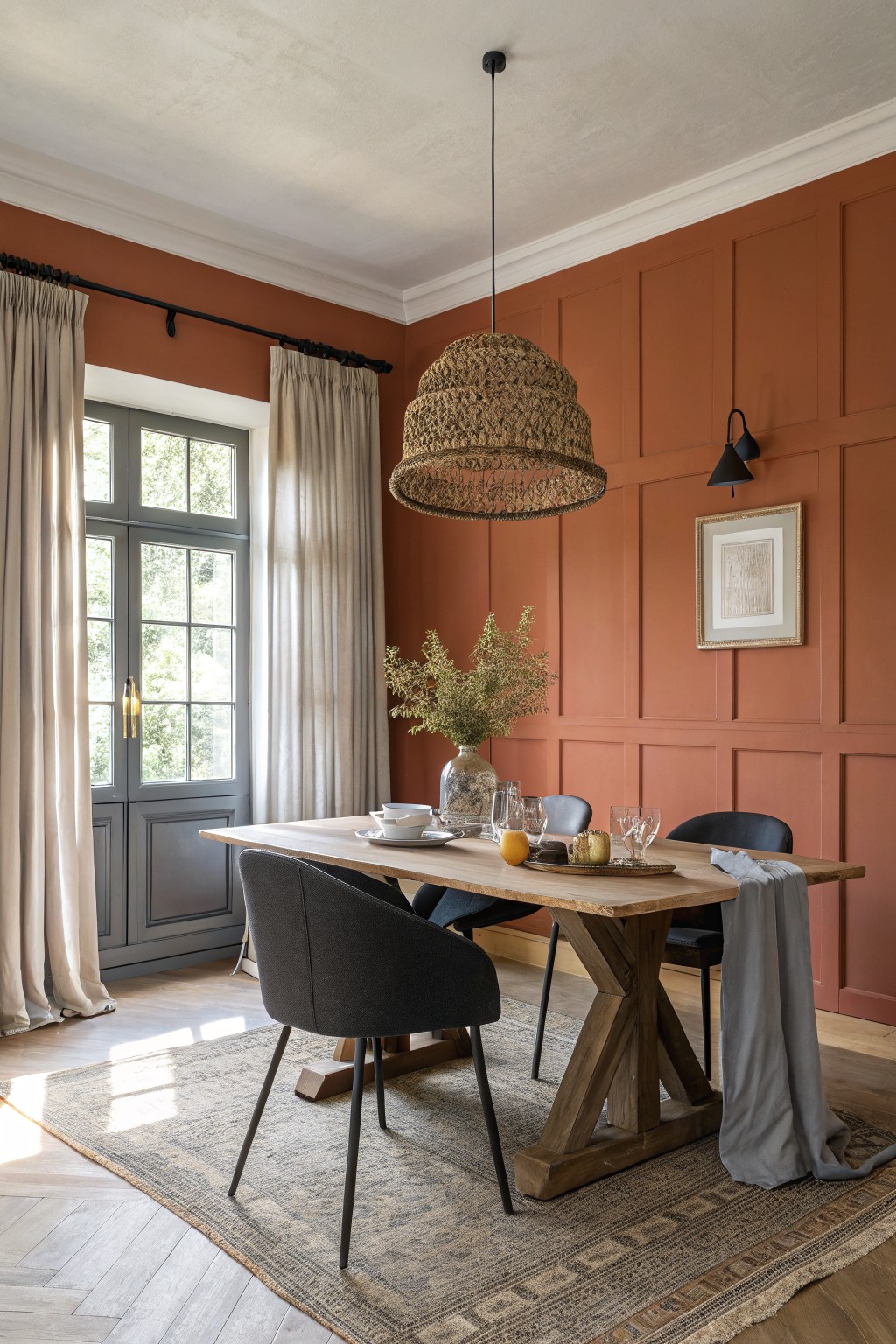 Dining room with warm terracotta walls and a wooden table set for a meal.