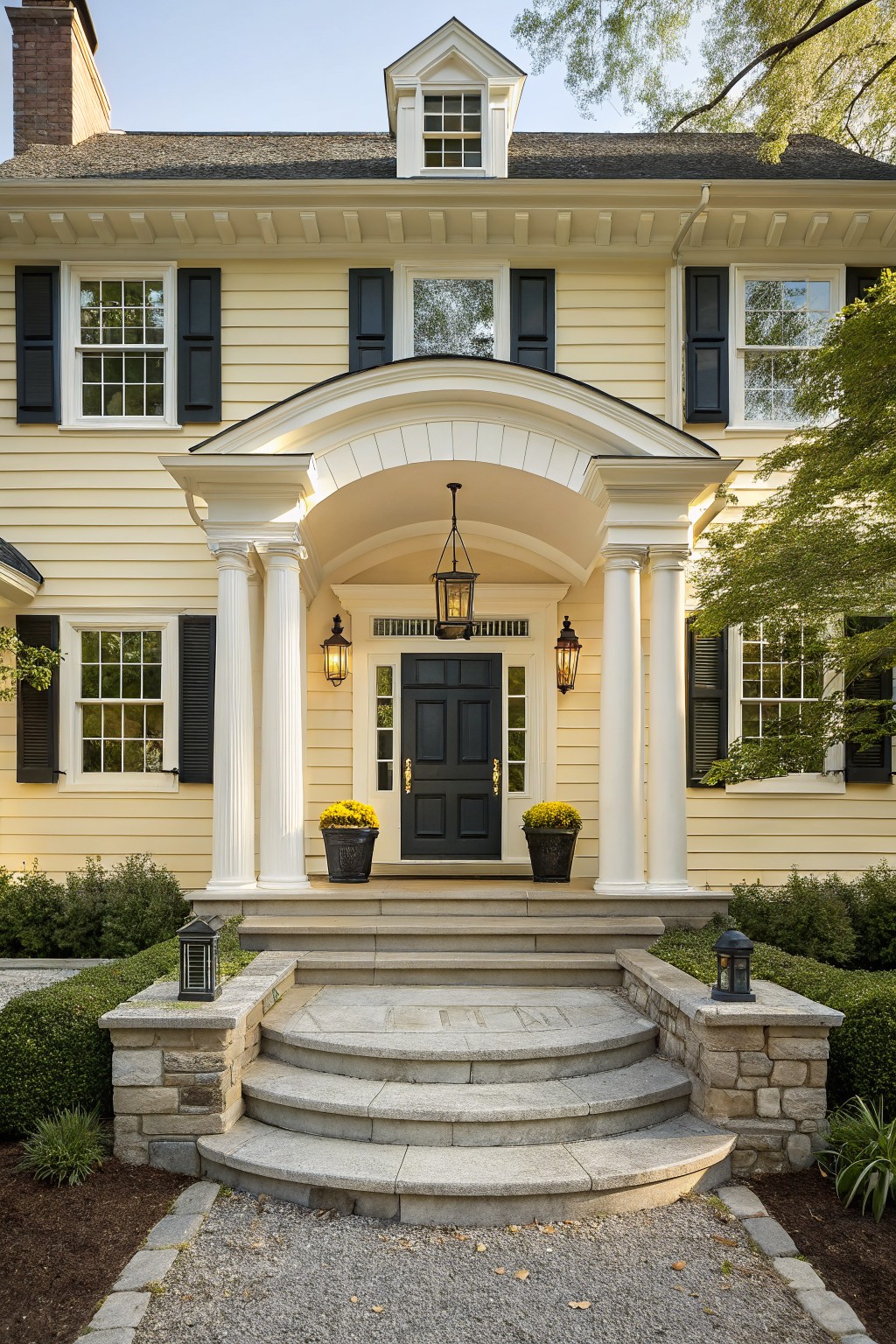 Elegant yellow house with dark shutters, white columns, and a black front door.