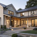 Two-story house with warm off-white siding and black window trim.