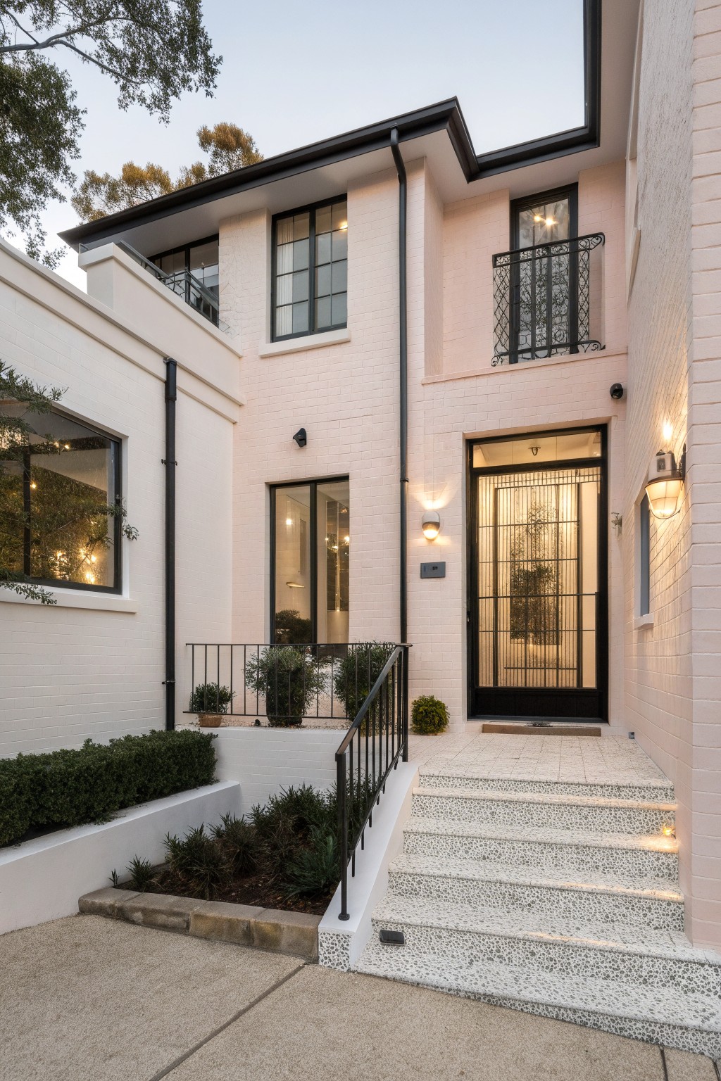 House exterior with soft pink painted brick and black window frames.