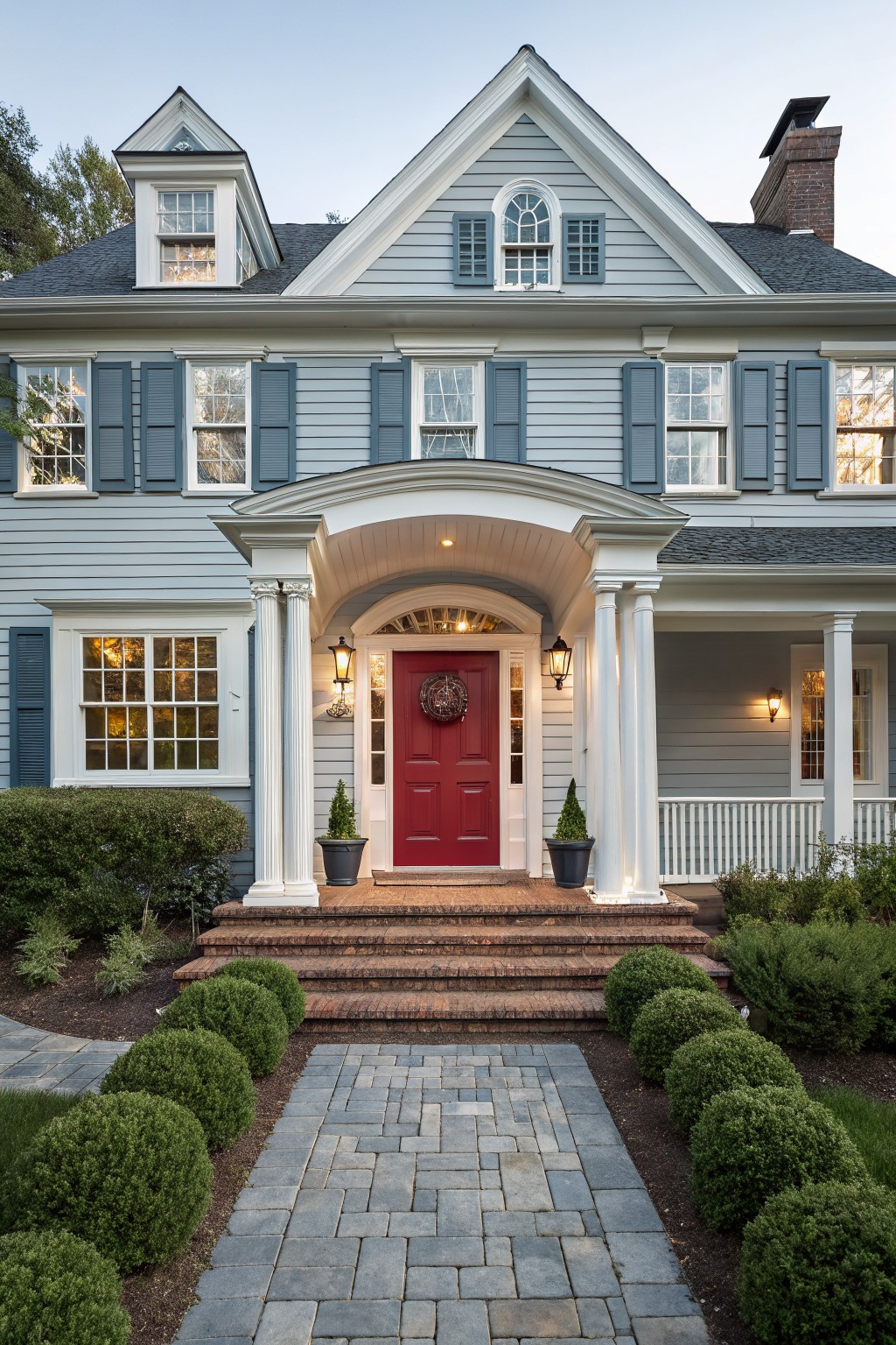 A house exterior painted in soft blue gray siding with white trim and columns around the front entrance.