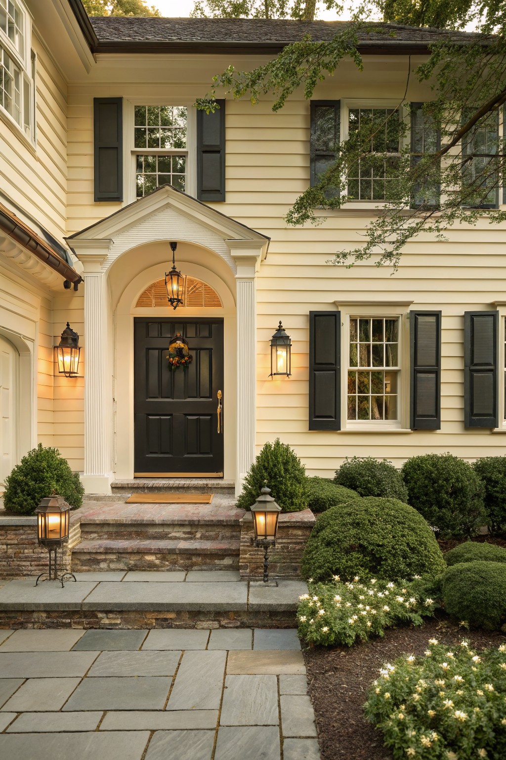 A house exterior with soft warm cream siding and dark shutters.