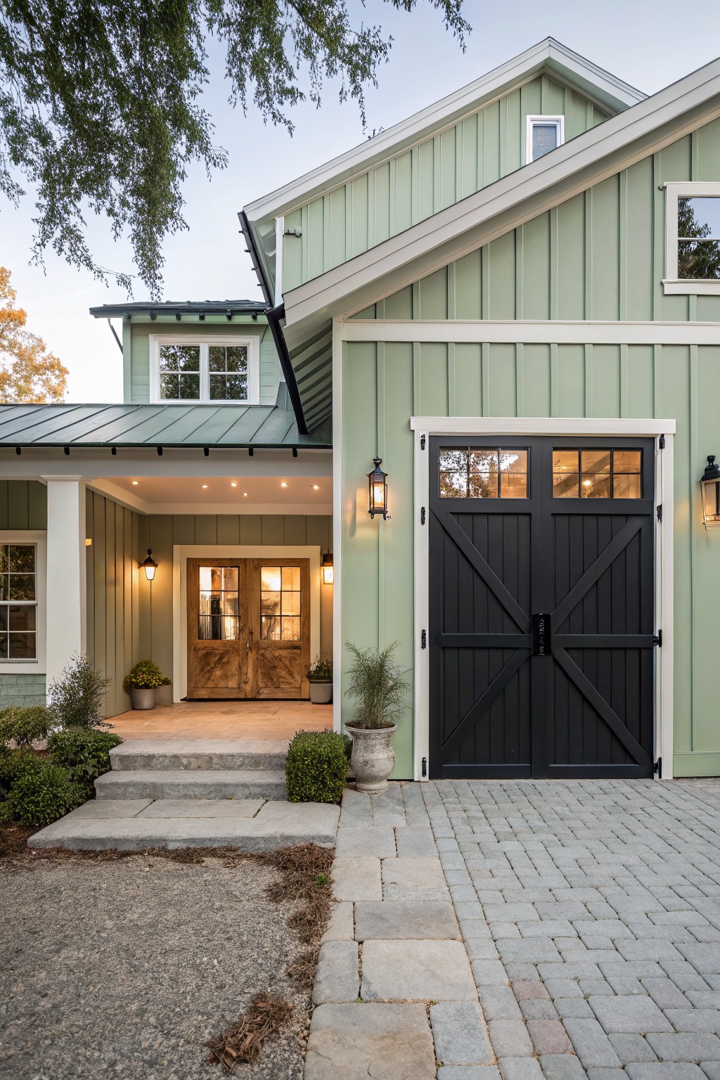 Light sage green siding on a house exterior with white trim and black doors.