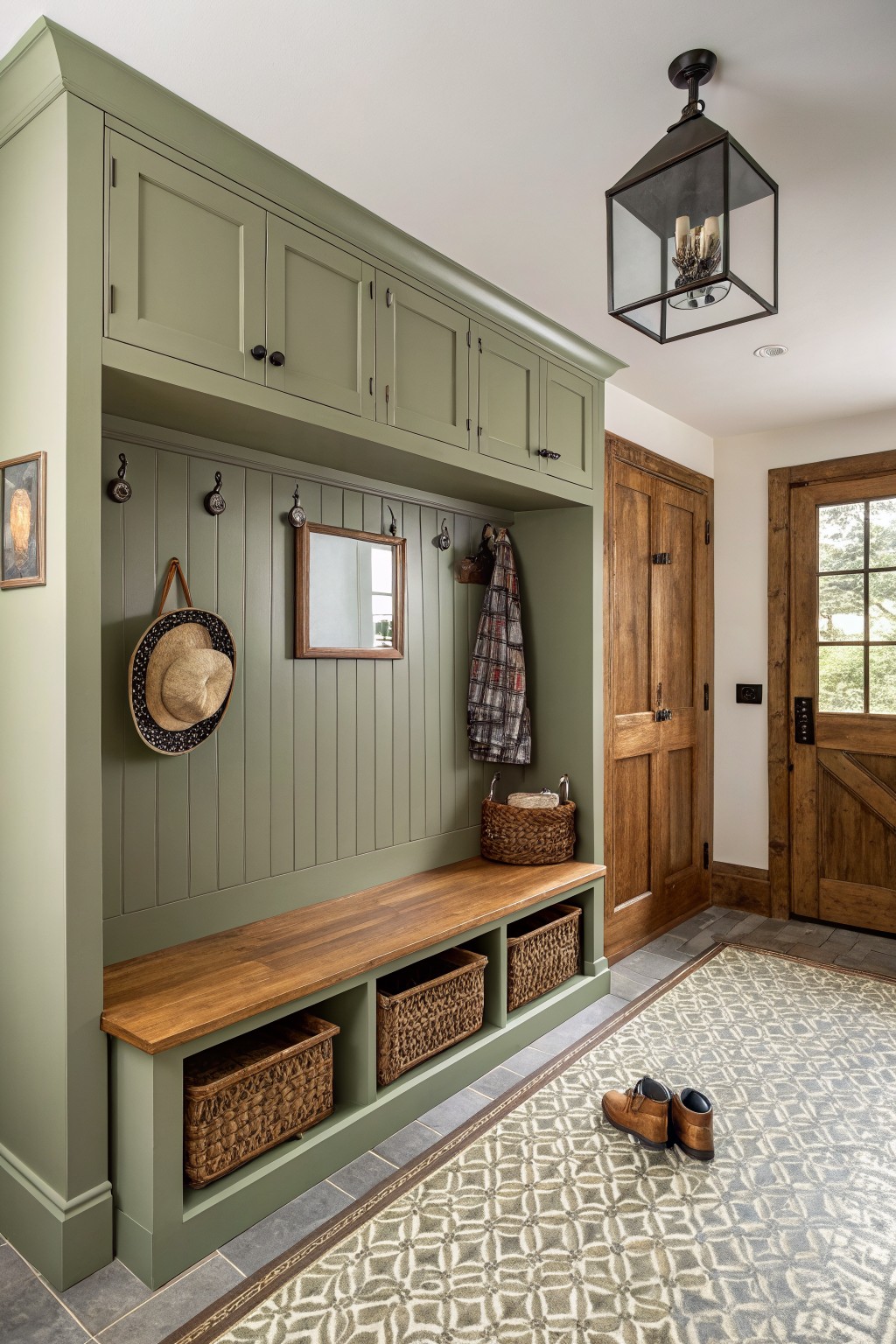 Soft sage green built-in bench and cabinetry in a home entryway.