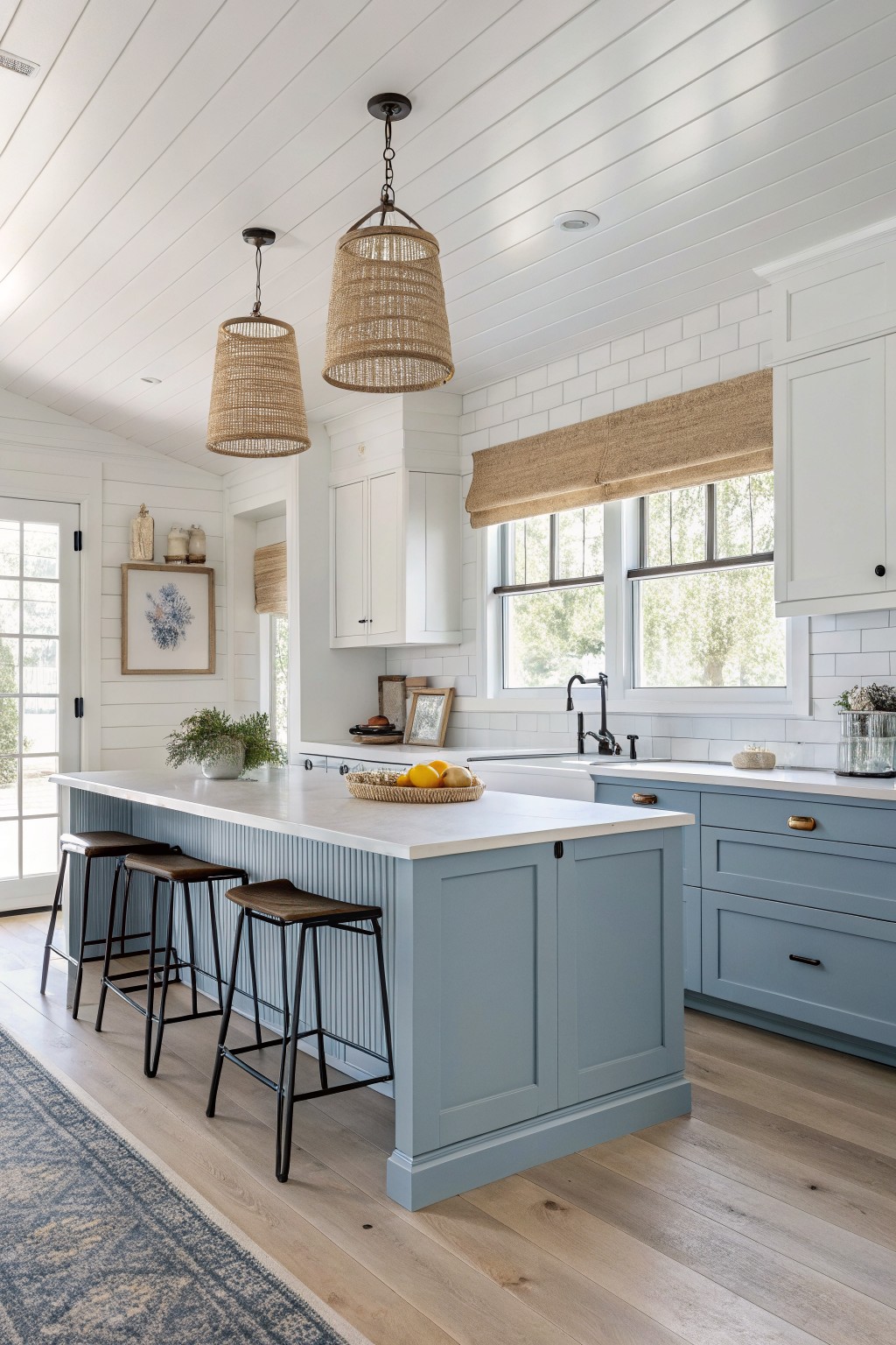 A kitchen island painted in soft blue gray with white countertops and black bar stools.