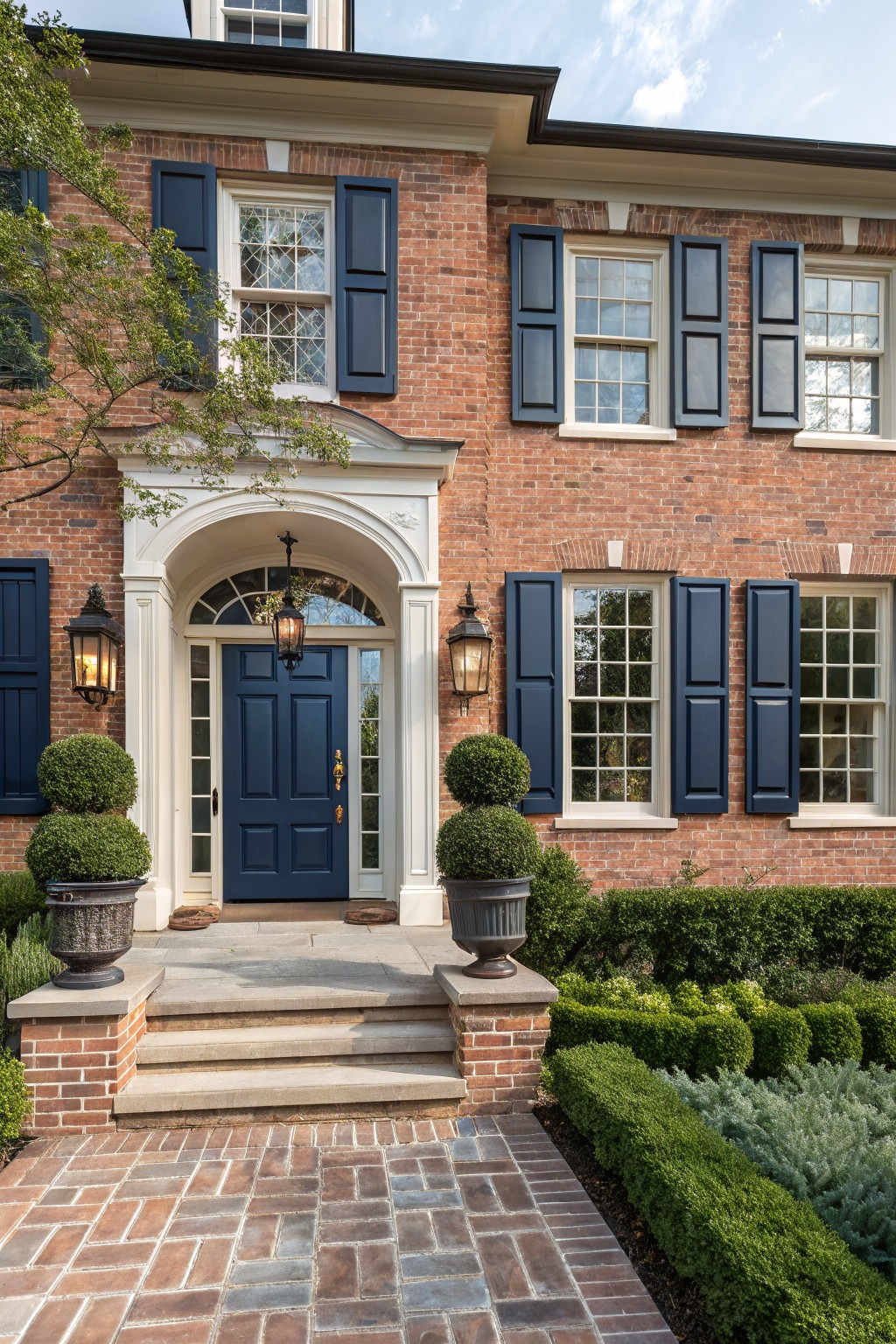 A brick house exterior with a deep navy blue front door and matching shutters.
