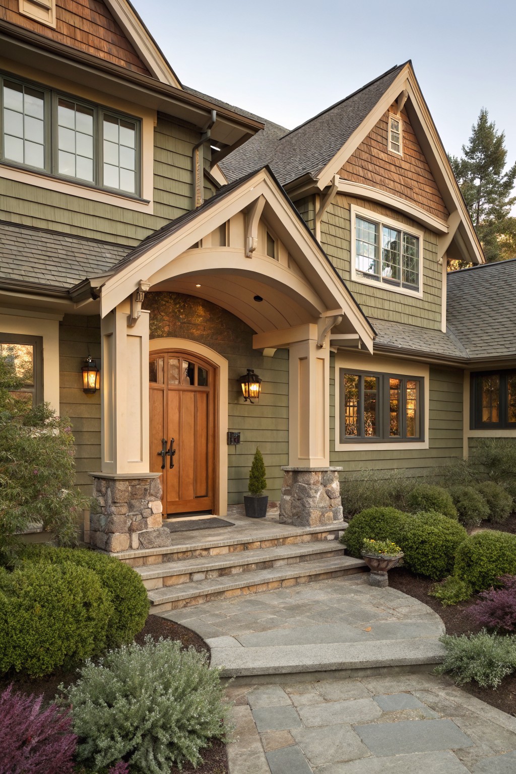 The house exterior shows soft sage green siding with stone columns at the entry.