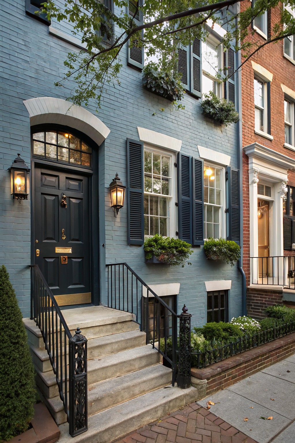 A townhouse exterior painted in soft blue gray with white trim and dark shutters.