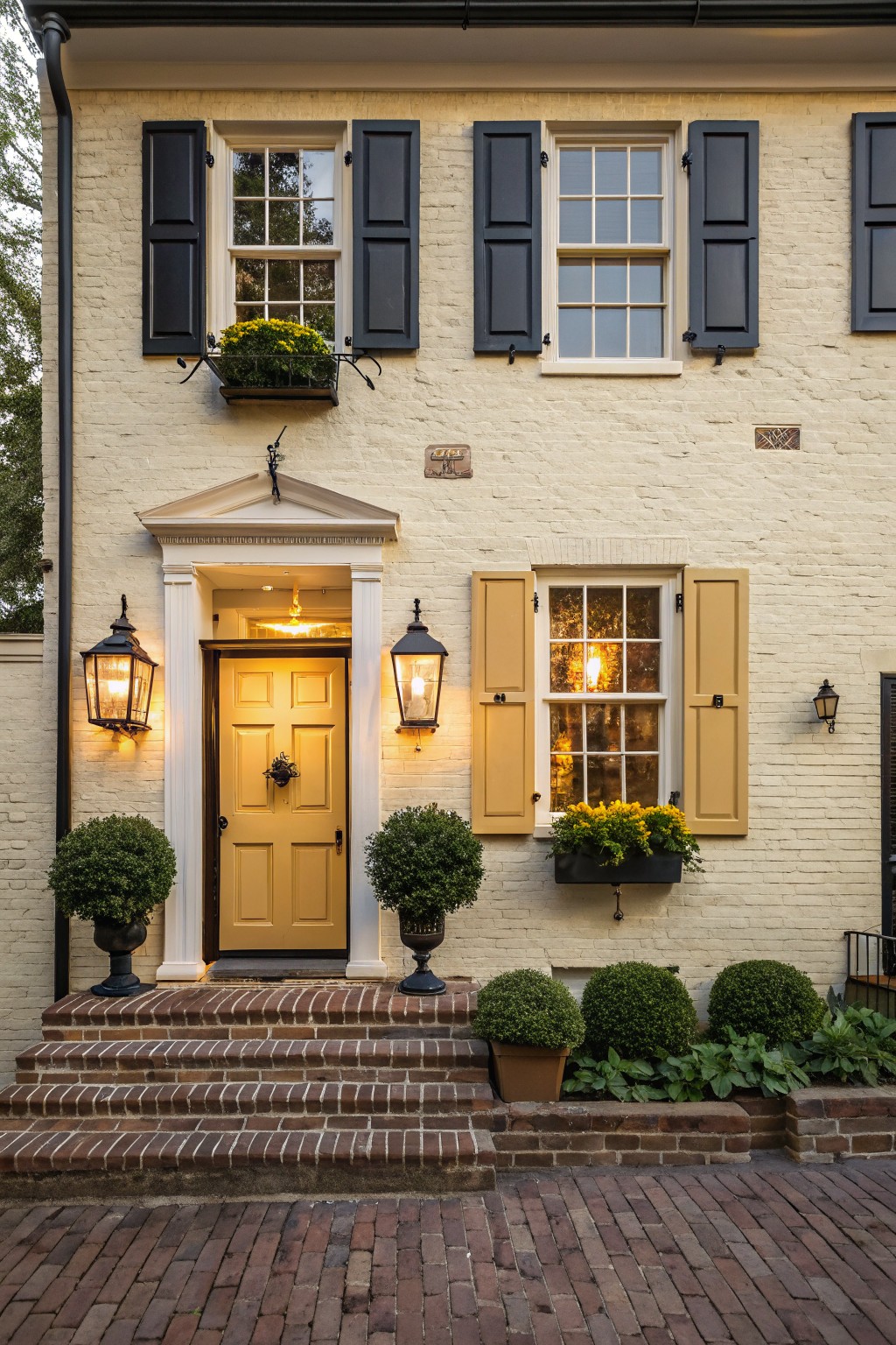 The front of a brick house painted in a soft creamy white.