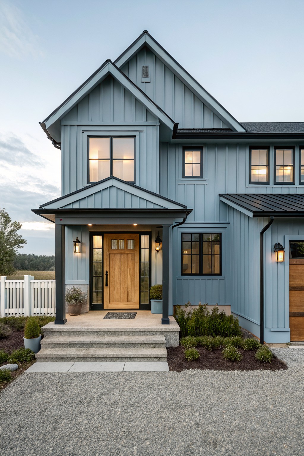 A house exterior painted in soft blue gray siding with black trim and a wooden door.