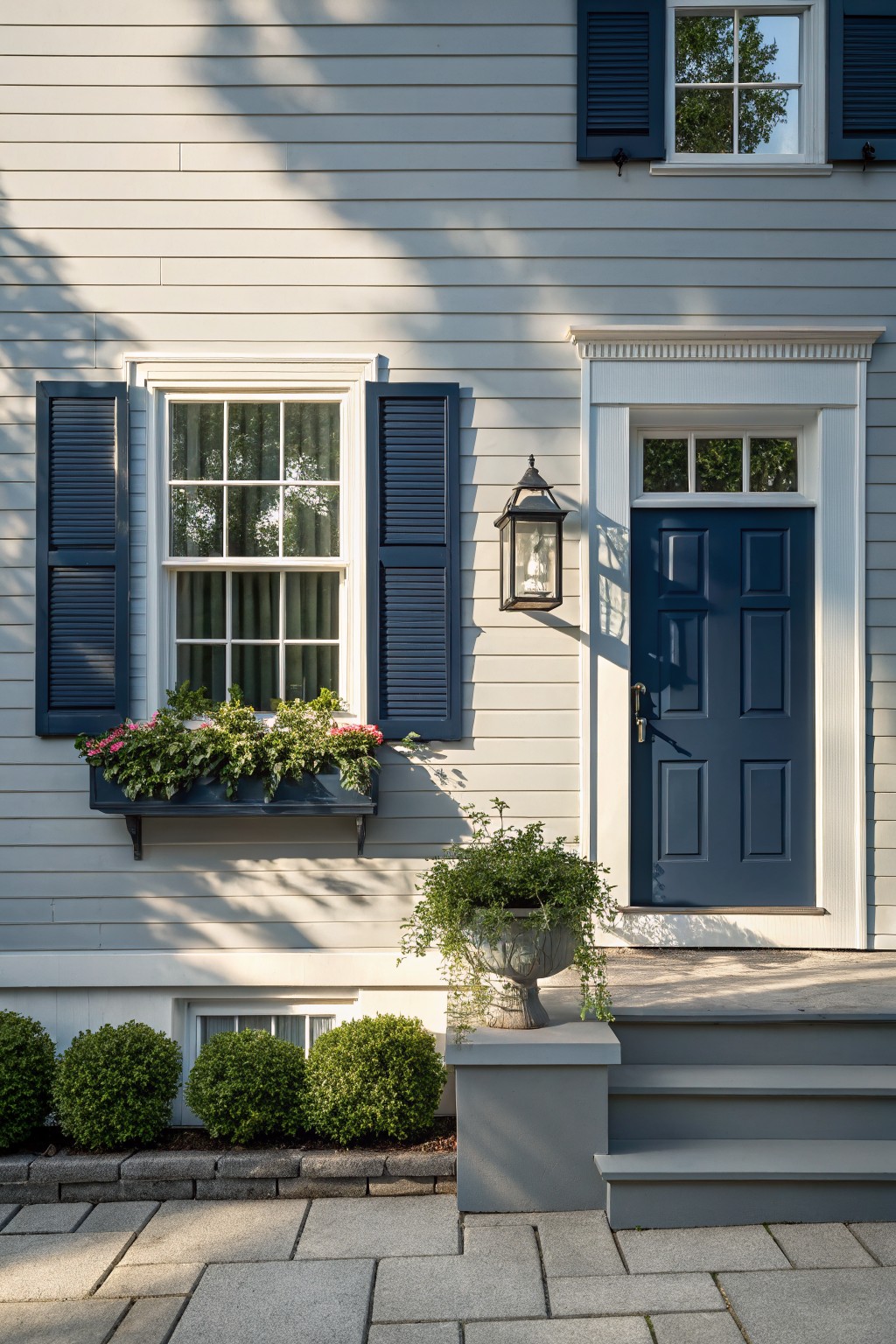 A house exterior with soft light gray siding and navy blue trim around the door and window.