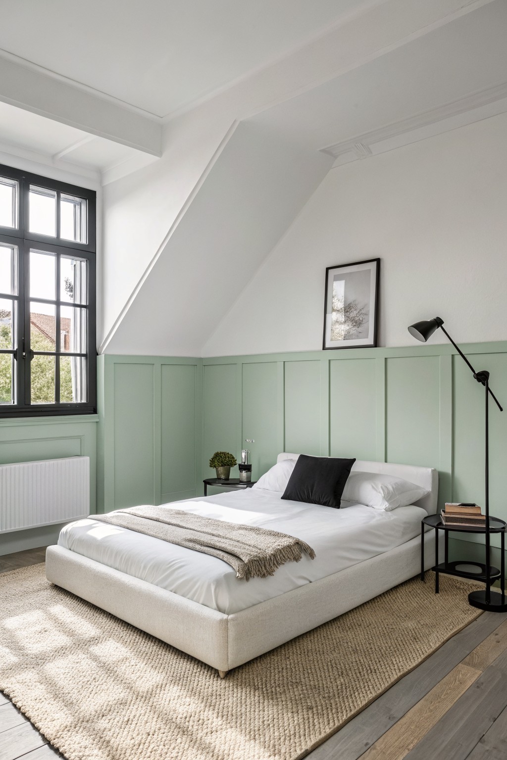 A bedroom with soft sage green paneled walls and white bedding.
