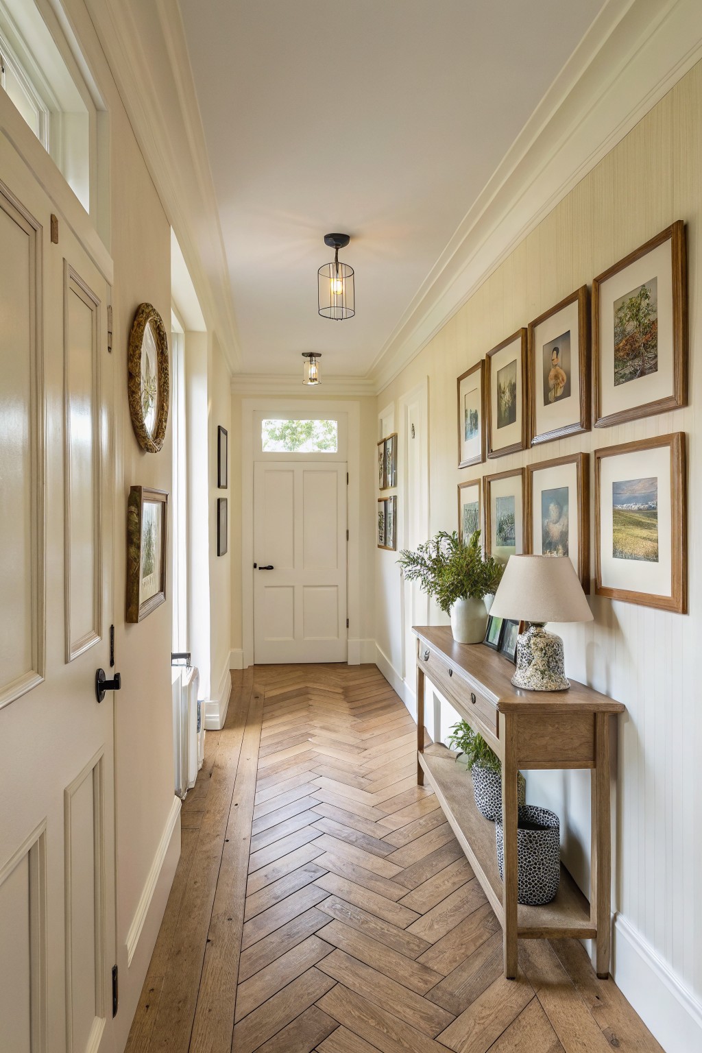 Hallway with warm off white walls and wood flooring.