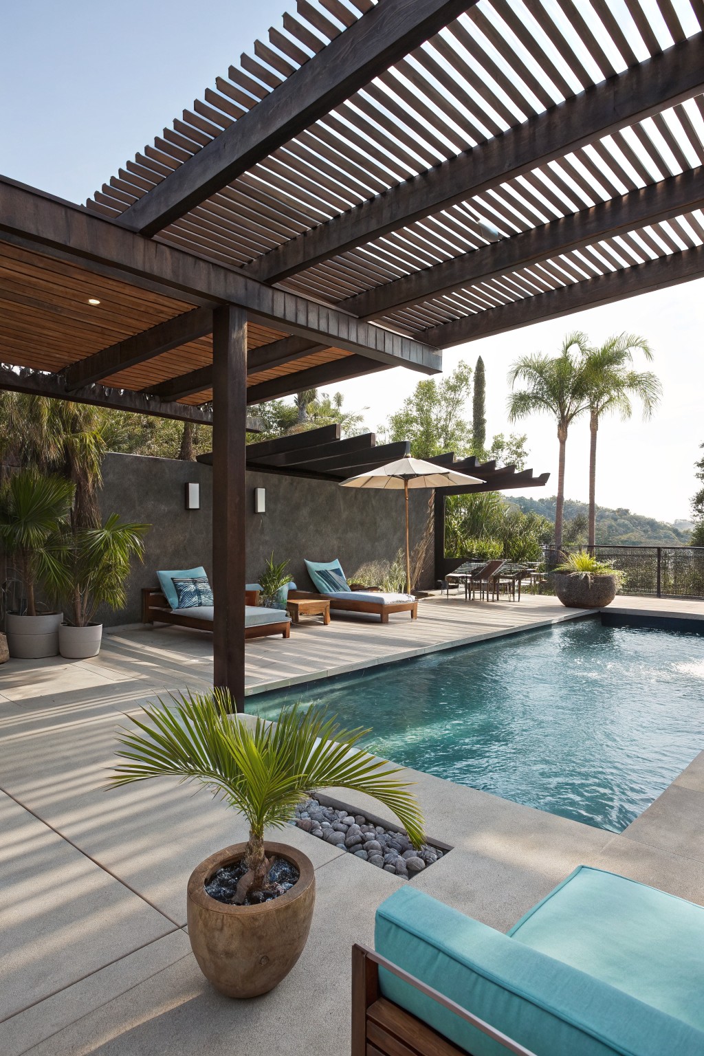 A backyard pool area with a large dark wooden pergola covering lounge chairs on a deck, next to a swimming pool and several potted plants.