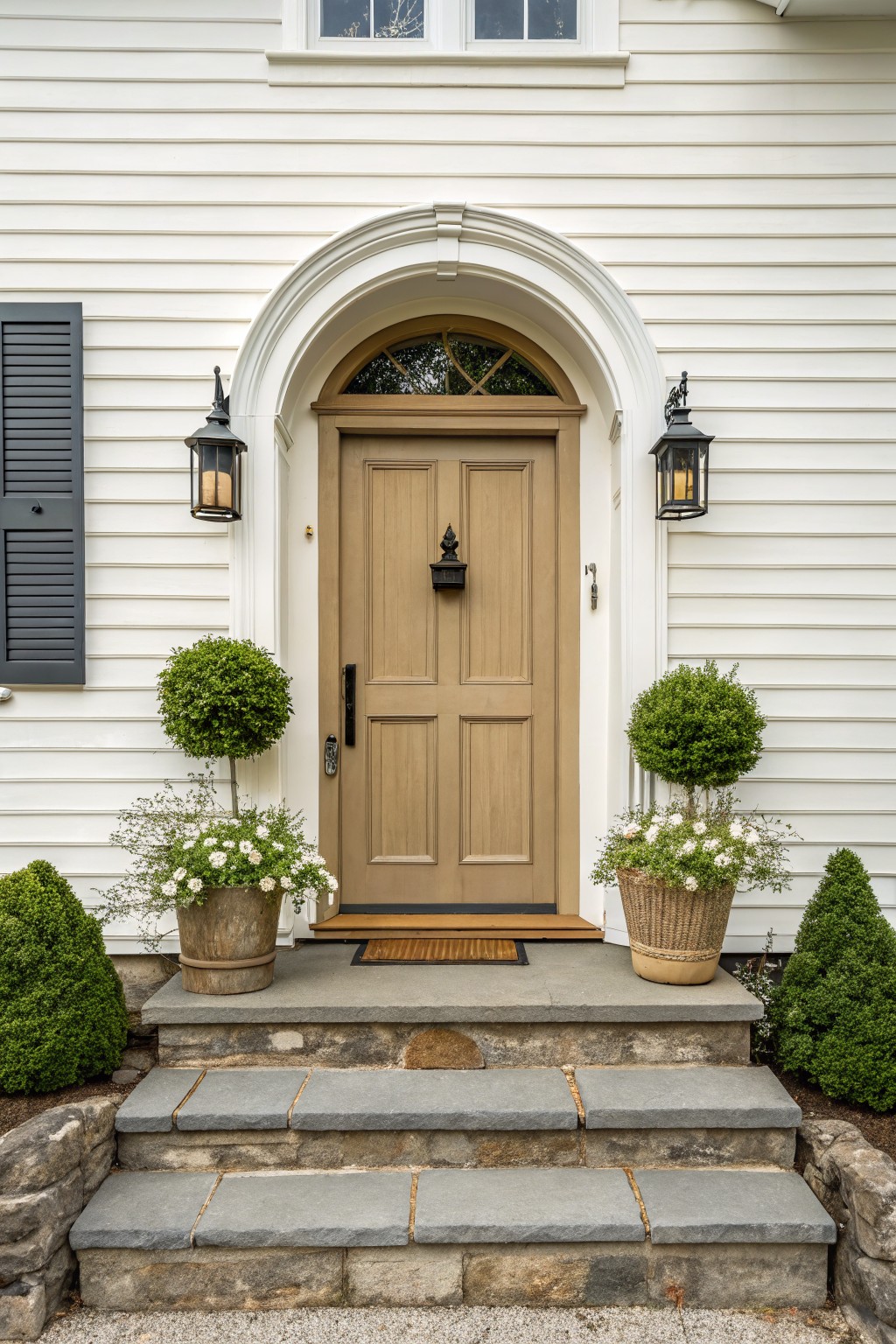 A light warm gray door on a white farmhouse exterior with stone steps.