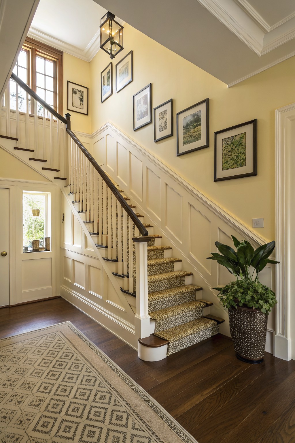 A staircase with soft yellow walls and white wainscoting.