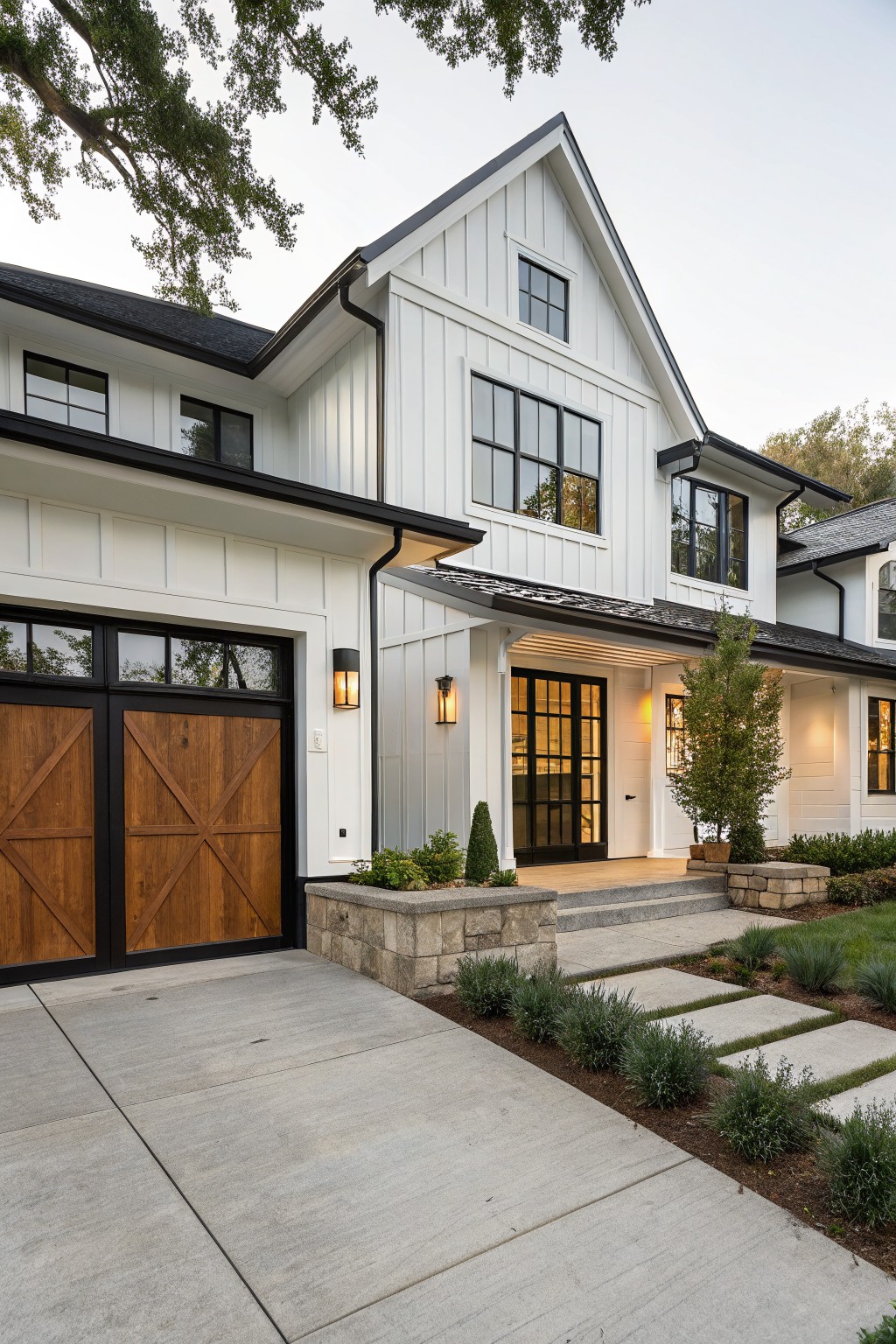 Modern white house with black trim, wooden garage doors, and stone steps