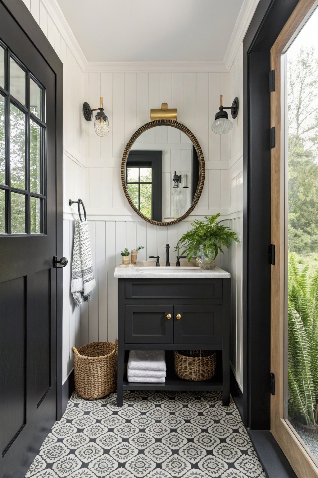Black vanity sink with round gold mirror, patterned tile floor, and open door