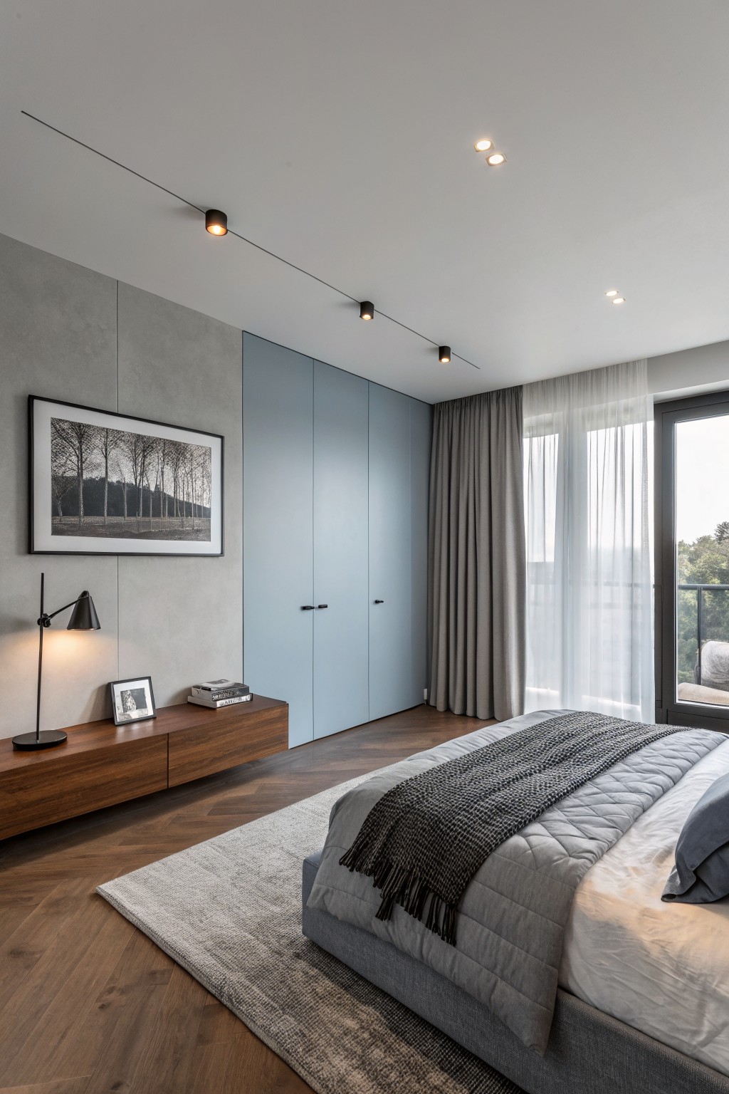 Modern bedroom with blue wardrobe, gray bed, wood floors, and large window.