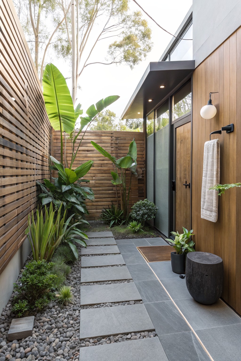 Modern courtyard path with stepping stones, tropical plants, and wooden walls
