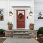 White farmhouse with a deep red front door and brick steps.