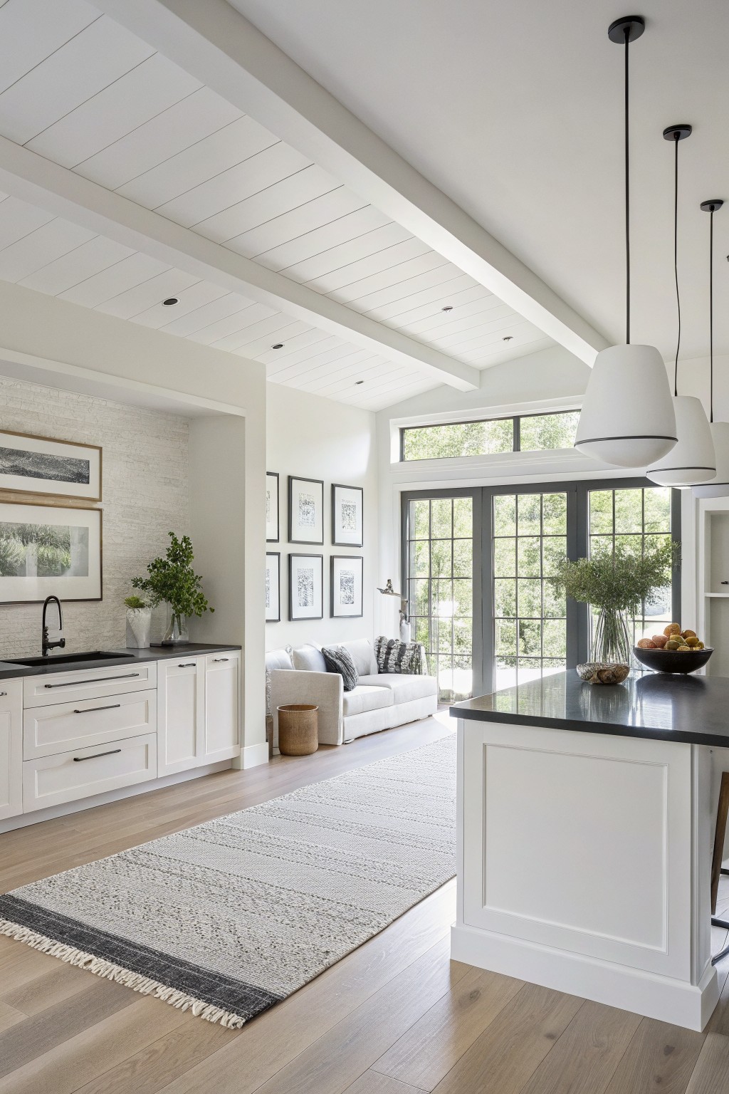 Bright white walls and cabinetry in an open kitchen and living area with wood floors.