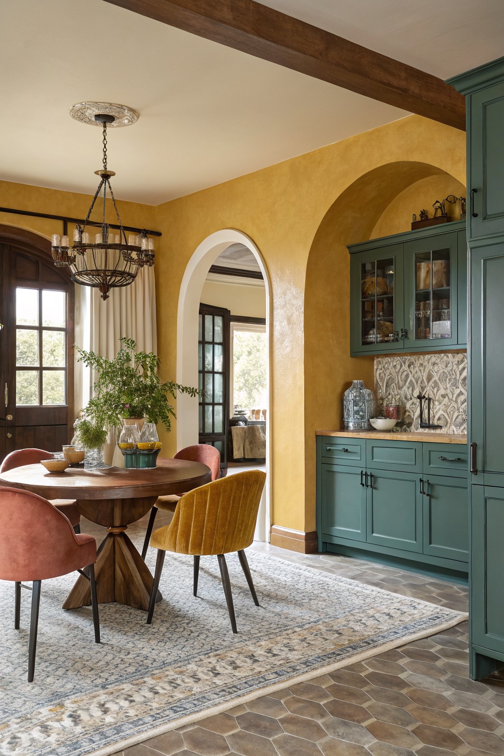 A dining space with warm yellow walls and teal kitchen cabinets.