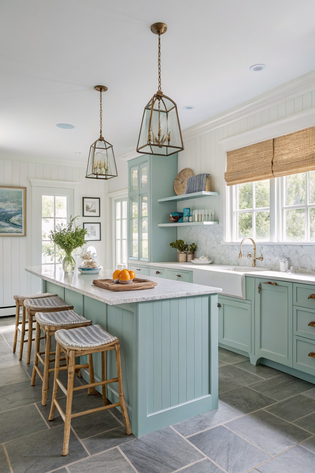 A kitchen with soft blue-green cabinets, white counters, and wood stools.