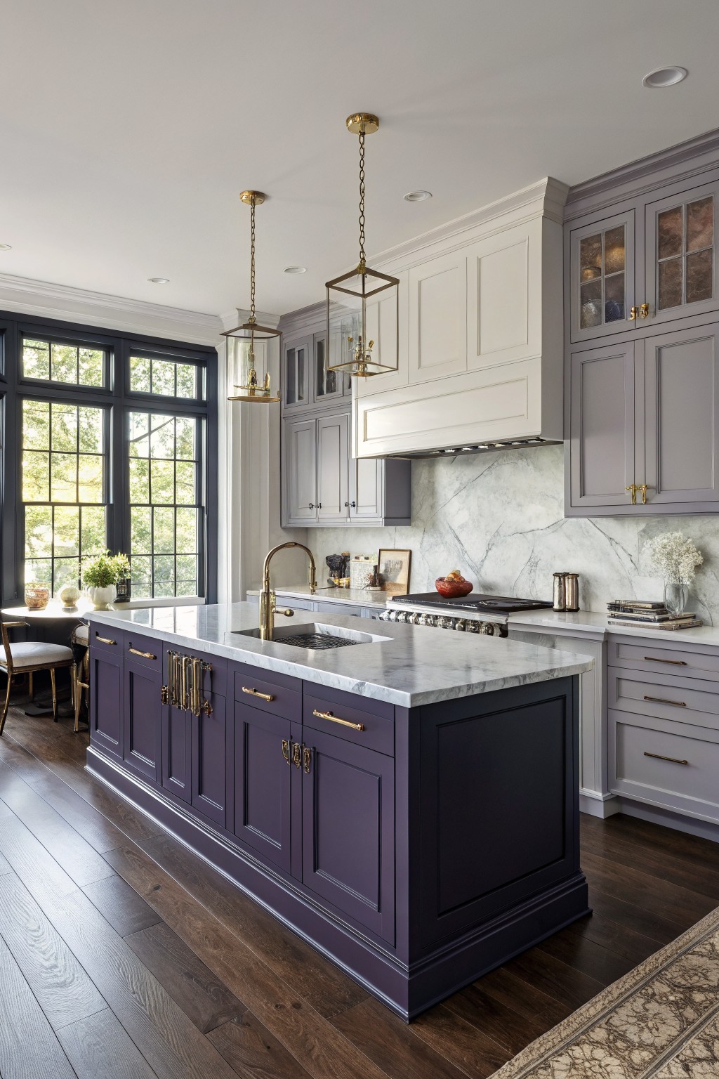 Luxurious kitchen with deep purple island, marble counters, white cabinets, and gold accents.