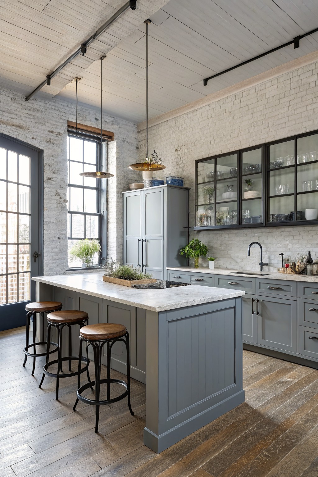 Blue gray cabinets in a kitchen with white brick walls and a large island.