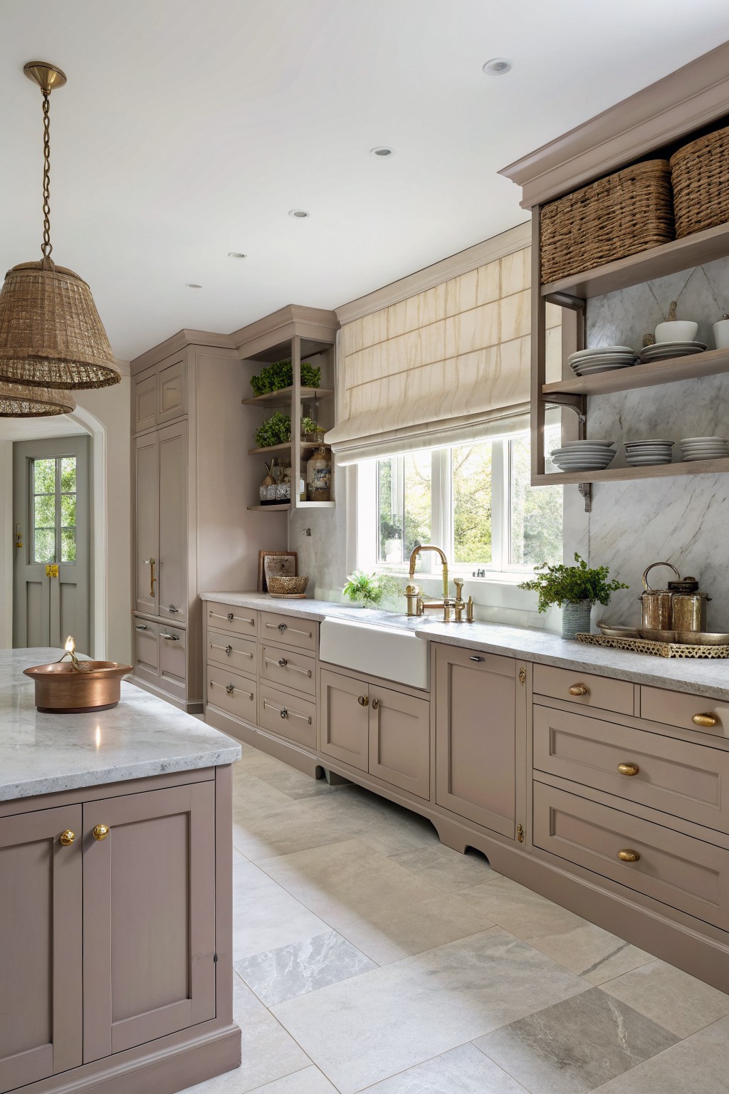 Warm greige cabinets in a neutral kitchen with marble counters.
