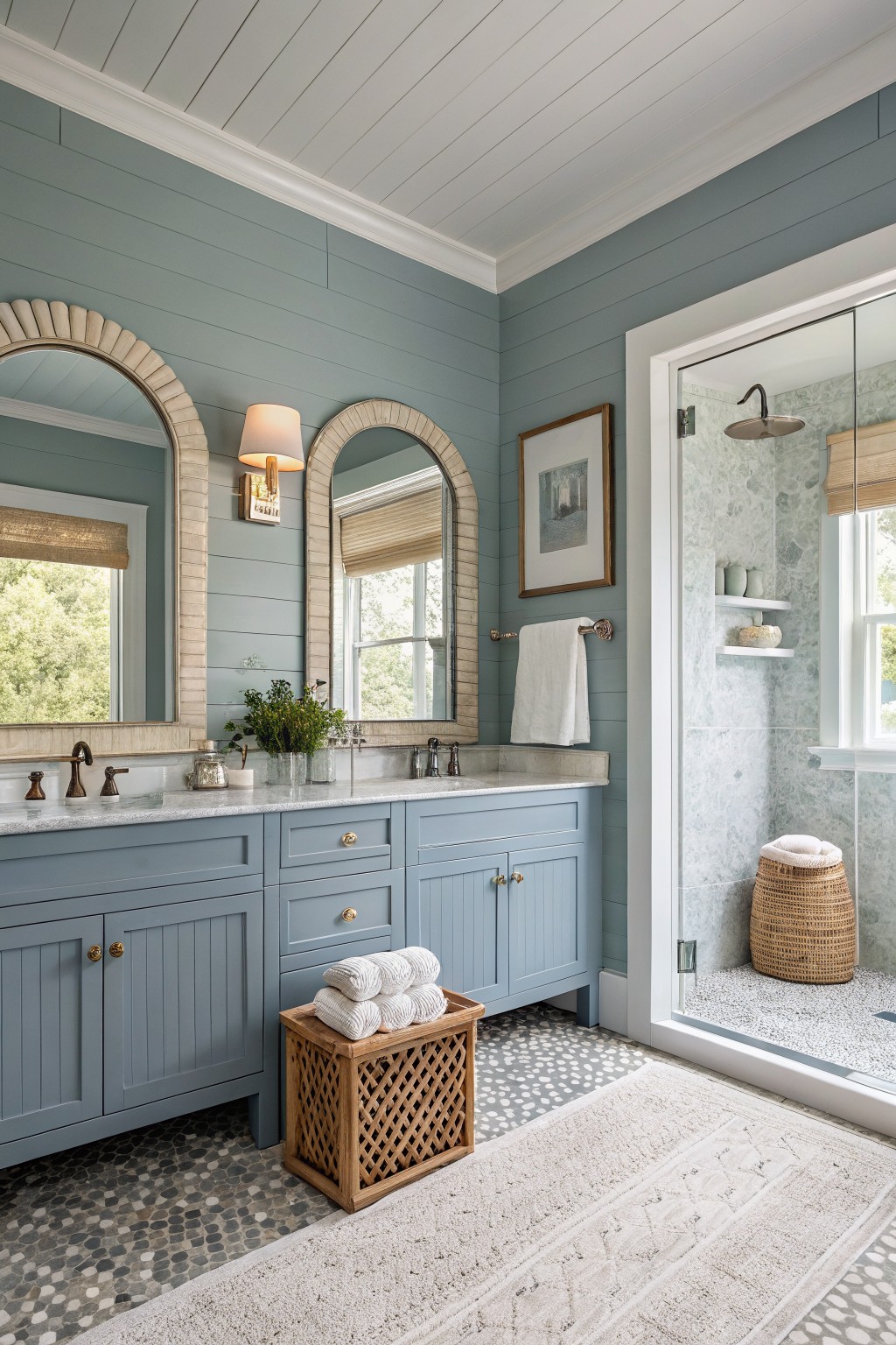 Bathroom walls painted in a soft blue gray tone with matching vanity and arched mirrors.