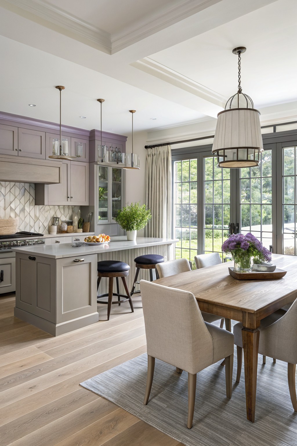 Kitchen cabinets painted in a soft greige color sit above light wood floors.
