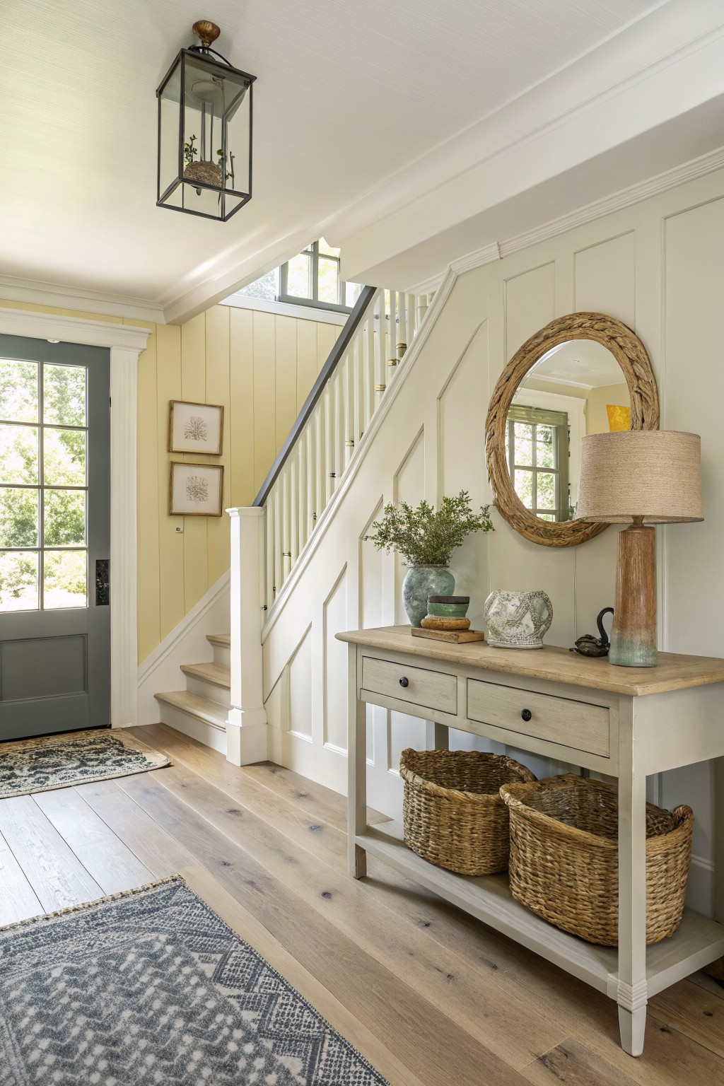Soft sage green walls in an entryway with light wood floors and white trim.