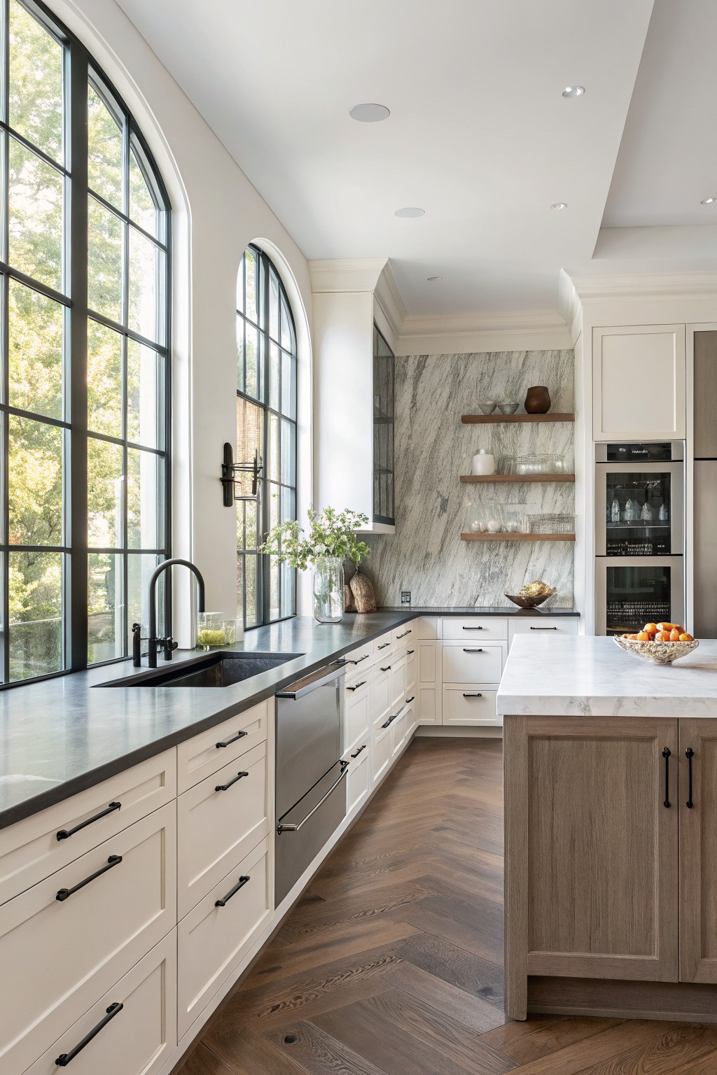 Creamy white kitchen cabinets in a bright space with dark counters and wood flooring.