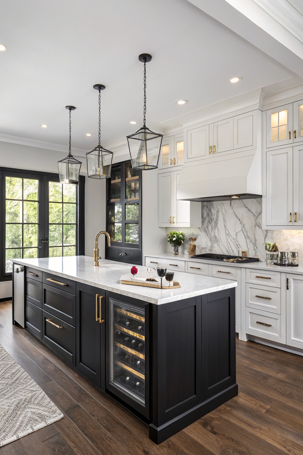 Kitchen island painted in deep black with white marble top and brass pulls.