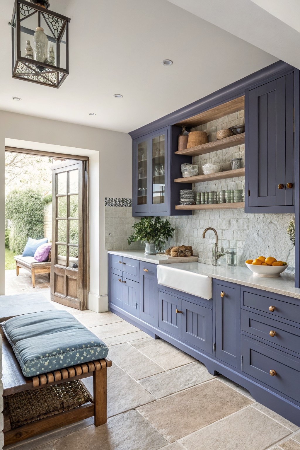 Blue gray cabinets in a kitchen with white counters and open wood shelves.