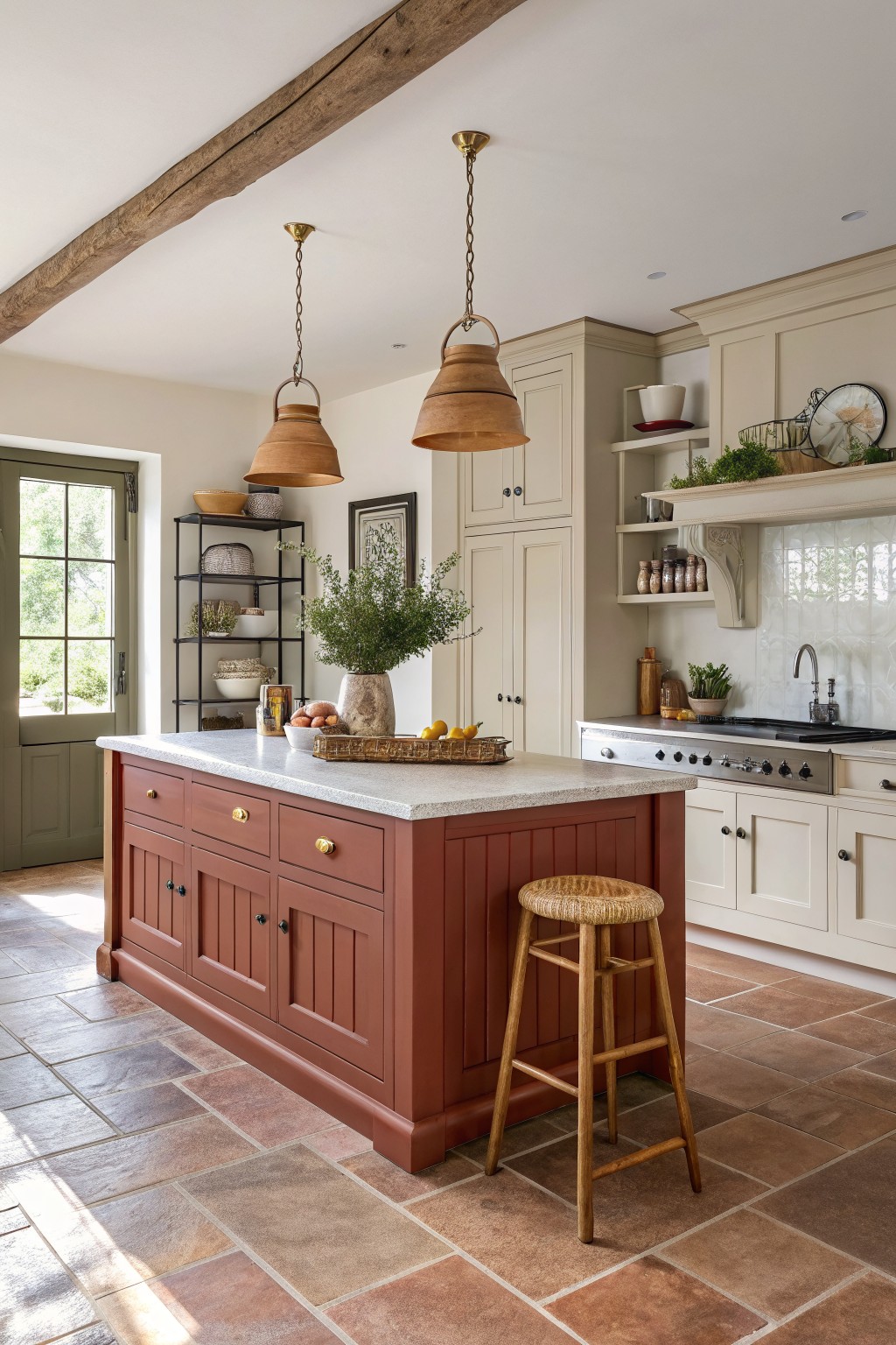 A kitchen island painted in warm terracotta red with cream cabinets behind it.